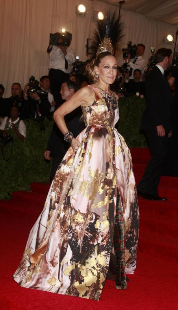 Sarah Jessica Parker in einem auffälligen Kleid und Kopfschmuck auf dem roten Teppich.