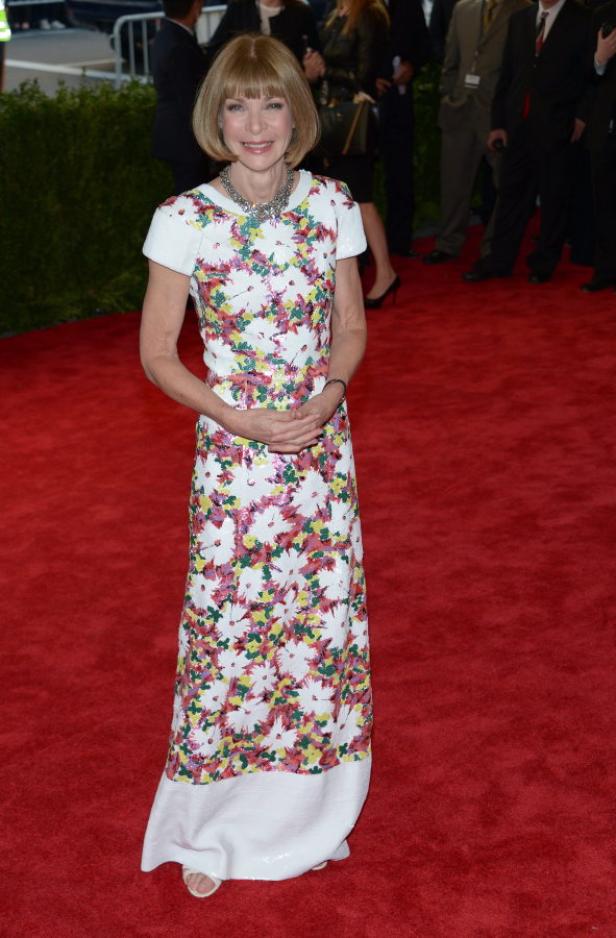 Anna Wintour auf einem roten Teppich in einem geblümten Kleid.