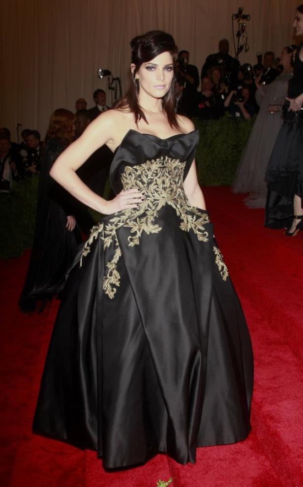 Ashley Greene in einer schwarzen Robe mit goldenen Verzierungen auf dem roten Teppich.