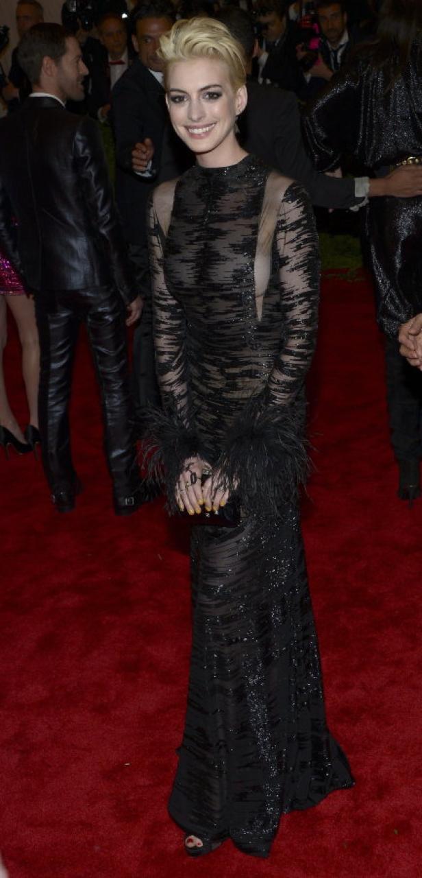 Anne Hathaway in einem langen, schwarzen Kleid auf einem roten Teppich.