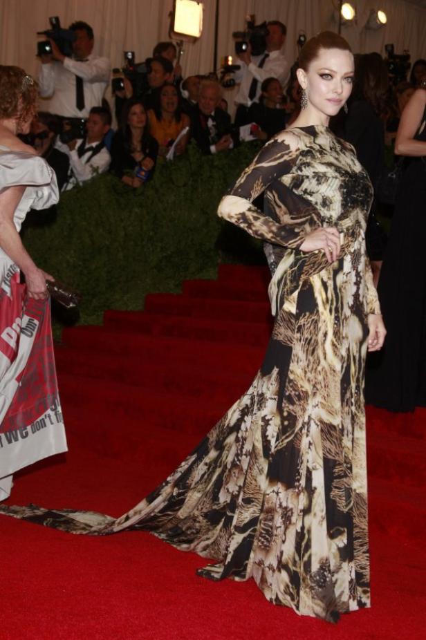 Amanda Seyfried in einem gemusterten Kleid auf einem roten Teppich.