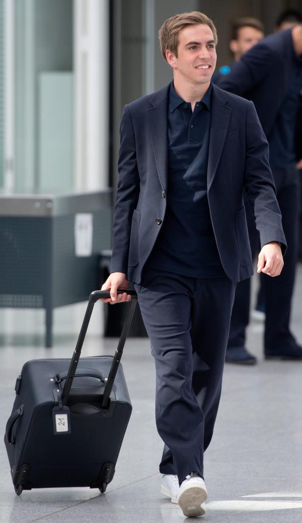 Ein Mann in einem Anzug zieht einen Rollkoffer.