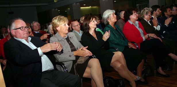 Zuschauer applaudieren bei einer Veranstaltung in einem Saal.