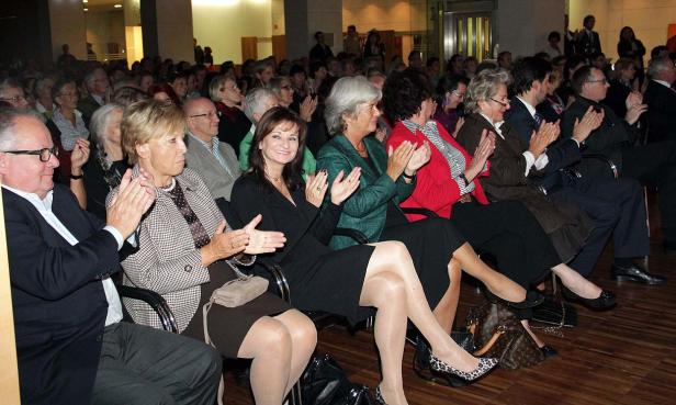 Ein Publikum sitzt und applaudiert bei einer Veranstaltung.