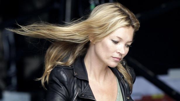 Kate Moss trägt eine schwarze Lederjacke und ihr blondes Haar weht im Wind.
