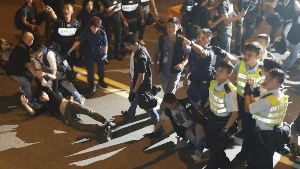 Polizisten nehmen eine am Boden liegende Person fest.