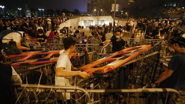 Menschen errichten eine Barrikade aus Absperrgittern und orangefarbenen Straßensperren.