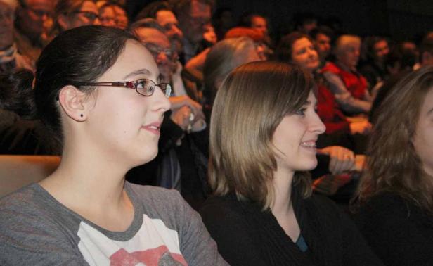 Zwei junge Frauen sitzen im Publikum und schauen aufmerksam zu.