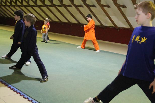 Eine Gruppe von Kindern trainiert Kung Fu in einer Halle.