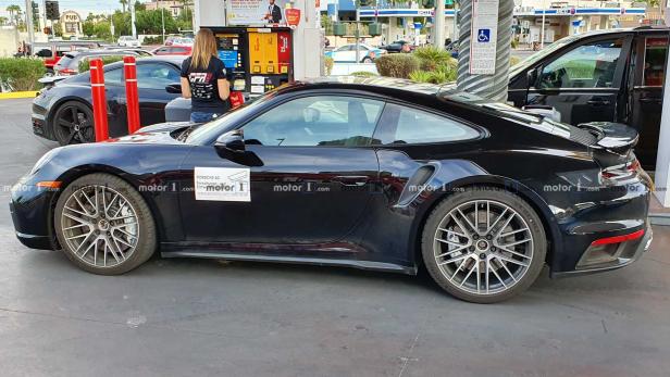Ein schwarzer Porsche wird an einer Tankstelle betankt.