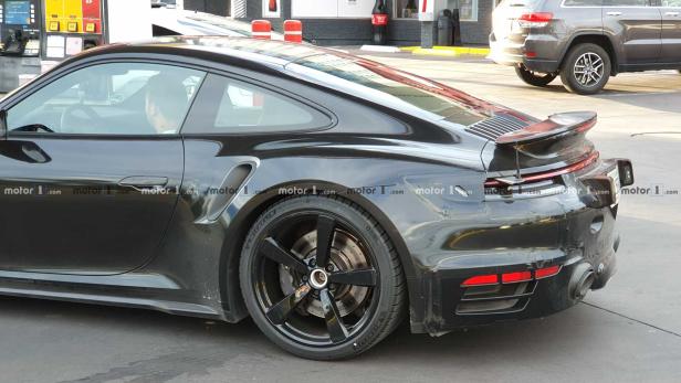 Ein schwarzer Porsche 911 parkt an einer Tankstelle.
