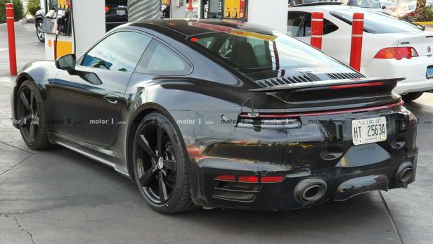 Ein schwarzer Porsche steht an einer Tankstelle.
