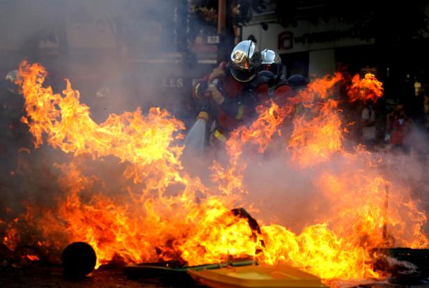 Firefighters extinguish a barricade during a protest urging authorities to take emergency measures against climate change in Paris