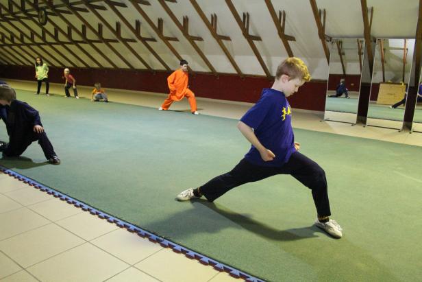 Eine Gruppe von Kindern übt Kampfsport in einer Turnhalle.