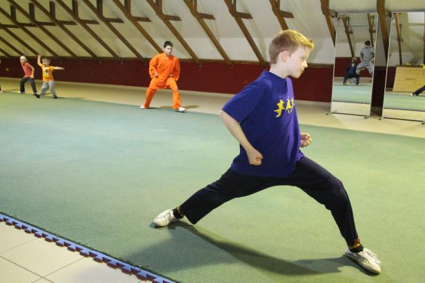 Kinder üben Kung Fu in einer Turnhalle.