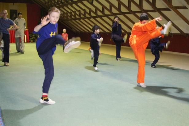 Eine Gruppe von Menschen, darunter Kinder, übt Kampfsport in einer Halle.