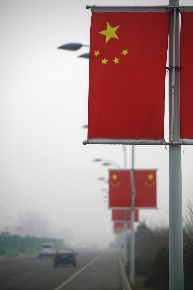 Eine Reihe chinesischer Flaggen säumt eine Straße an einem nebligen Tag.