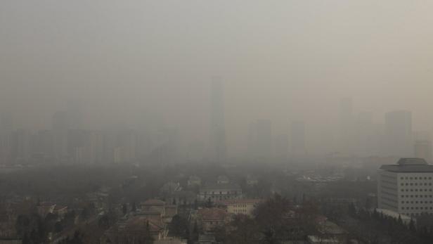 Eine Stadtansicht mit starkem Smog über Gebäuden und Bäumen.