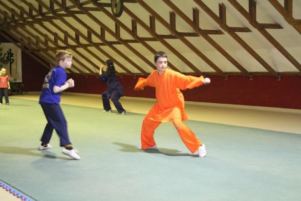 Kinder üben Kung Fu in einem Trainingsraum.