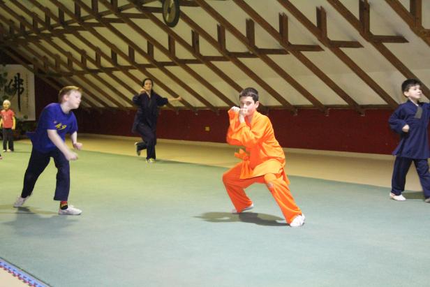 Kinder üben Kung Fu in einer Halle.