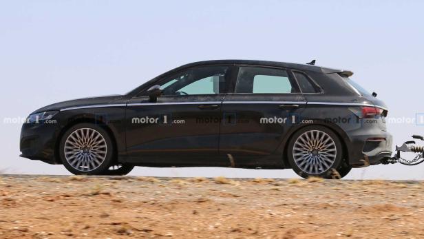 Ein schwarzer Audi A3 fährt auf einer Straße und zieht einen Anhänger.