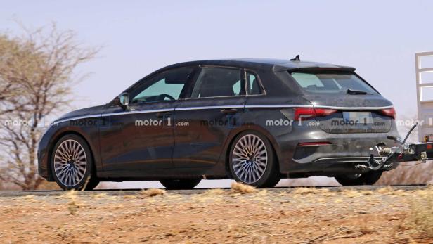 Ein grauer Audi A3 fährt auf einer Straße und zieht einen Anhänger.