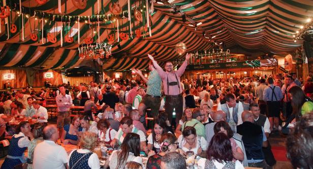 Volles Bierzelt mit Menschen in Tracht beim Oktoberfest.