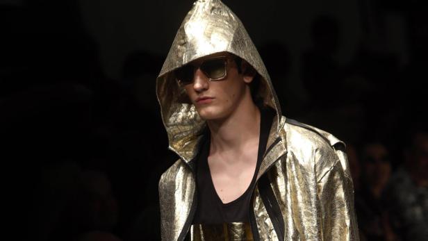 Ein Mann mit Sonnenbrille und goldener Jacke mit Kapuze.