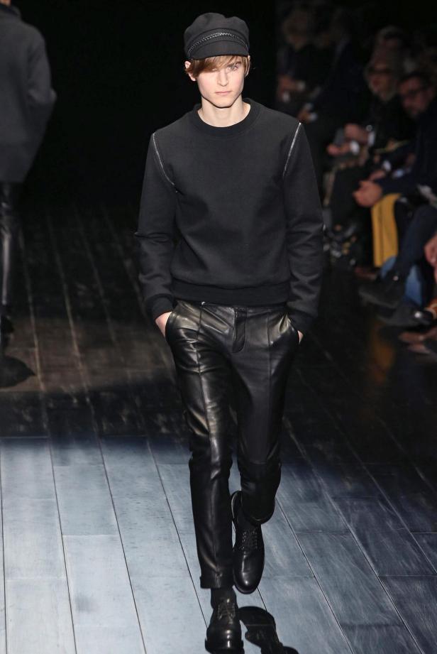 Ein Mann mit Schirmmütze und Lederhose läuft über einen Laufsteg.