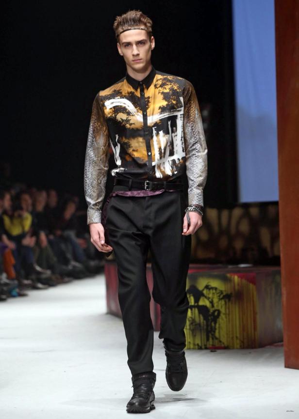 Ein Mann mit gemustertem Hemd läuft auf einem Laufsteg.