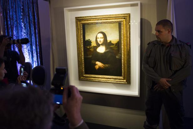 Besucher fotografieren die „Mona Lisa“, die von einem Wachmann bewacht wird.