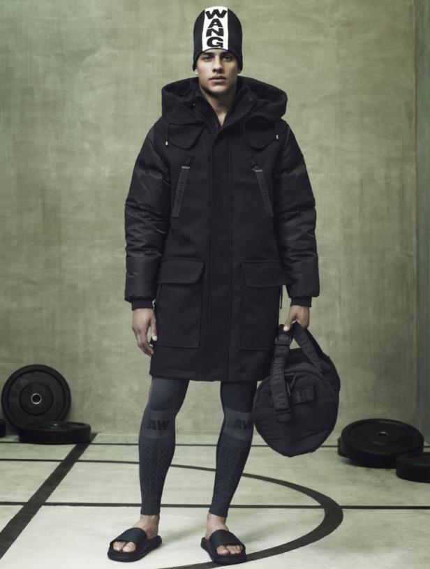 Ein Mann in Sportbekleidung und Winterjacke steht in einer Turnhalle.