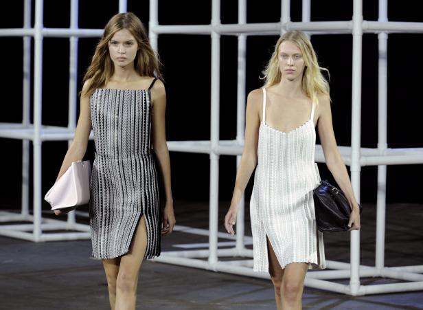 Zwei Models präsentieren Kleider mit vertikalen Streifen auf einem Laufsteg.