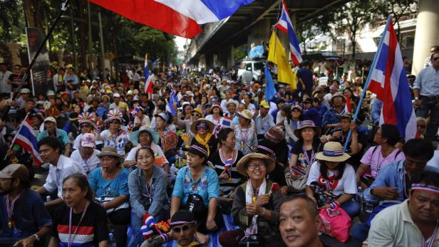 Eine große Menschenmenge mit thailändischen Flaggen demonstriert auf einer Straße.