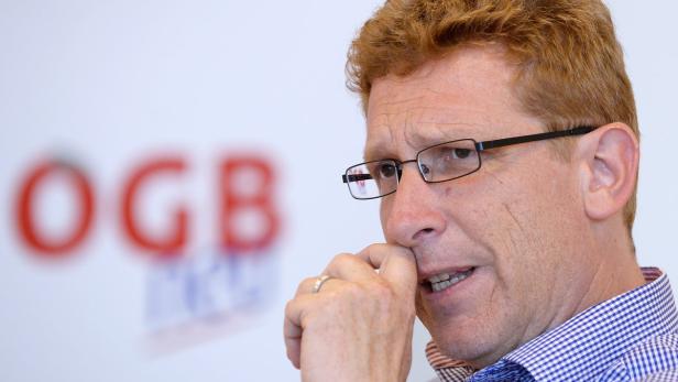 Ein Mann mit Brille und kariertem Hemd vor dem Logo der Gewerkschaft ÖGB.