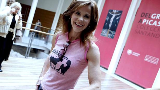 Eine lächelnde Frau in einem rosa T-Shirt mit dem Logo der Miranda Blake World Heart Foundation.