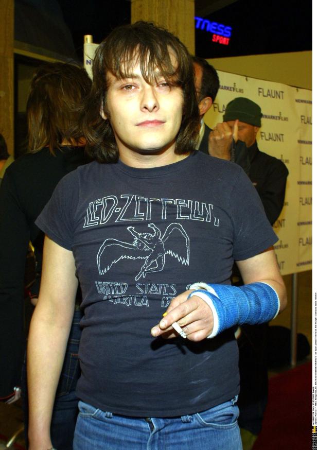 Edward Furlong mit Gips am Arm und Led-Zeppelin-T-Shirt raucht eine Zigarette.