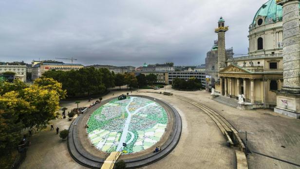 Blick auf den Karlsplatz in Wien mit der Karlskirche und einer großen Stadtkarte.