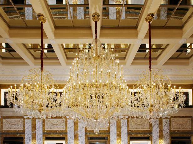 Ein großer, goldener Kronleuchter hängt in einem opulenten Raum.