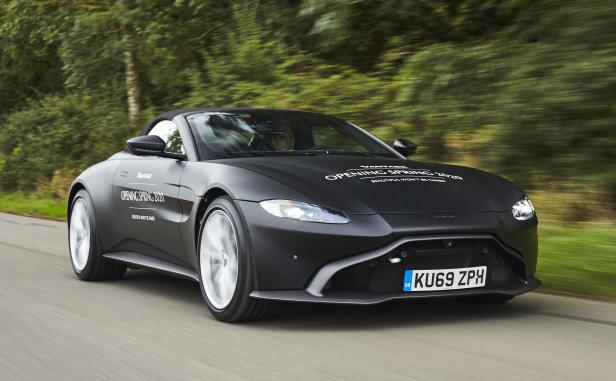 Ein schwarzer Aston Martin Vantage Roadster fährt auf einer Landstraße.