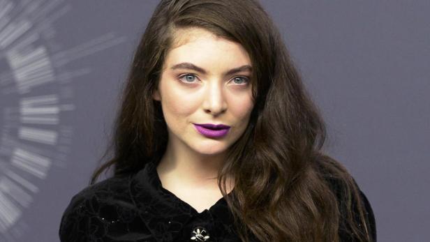 Porträt der Sängerin Lorde mit dunklem Haar und lila Lippenstift.