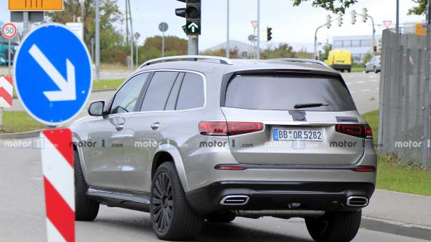 Ein silberner Mercedes-Benz SUV fährt auf einer Straße mit Verkehrsschildern.