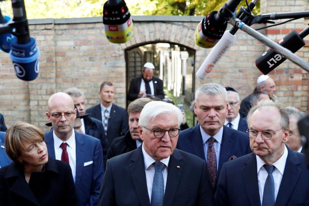 German President Frank-Walter Steinmeier speaks to the media next to his wife Elke Budenbender and Saxony-Anhalt State Premier Reiner Haseloff outside the synagogue in Halle