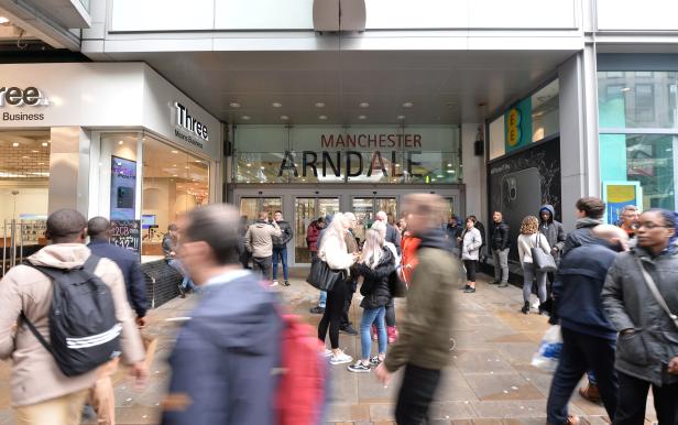 People walk past the entrance to the Arndale shopping centre after several people were stabbed in Manchester