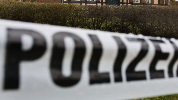 Ein Absperrband der Polizei vor einem Haus.