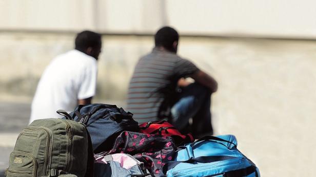 Zwei Männer sitzen hinter einem Haufen Gepäckstücke.