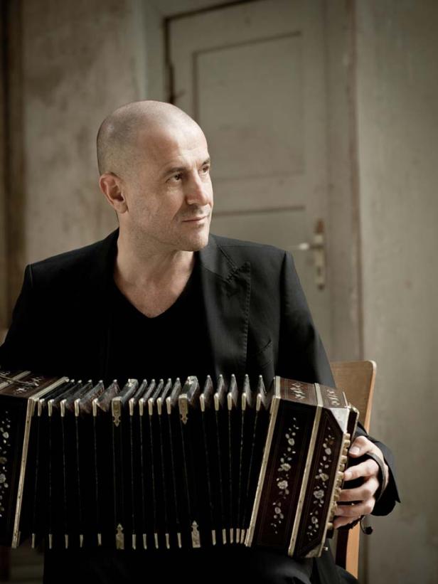 Ein Mann mit Glatze spielt ein Bandoneon.