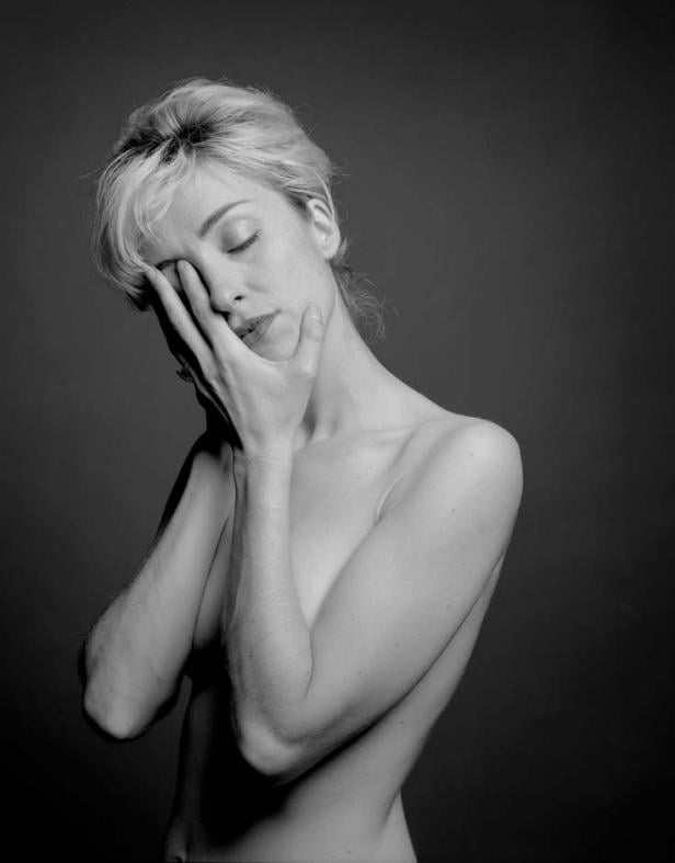 Eine Frau mit blonden Haaren bedeckt ihr Gesicht mit der Hand.