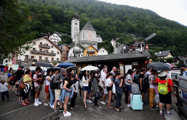 Tourists queue to board a boat for a trip on Hallstaettersee lake in Hallstatt