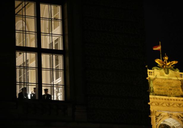 Drei uniformierte Männer stehen nachts an einem Fenster in Wien.